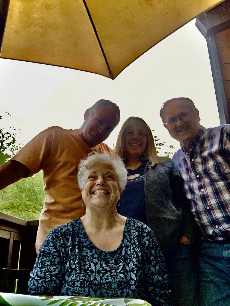 A group of people standing under an umbrella
Description automatically generated with medium confidence