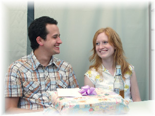 A person and person sitting at a table with a present

Description automatically generated