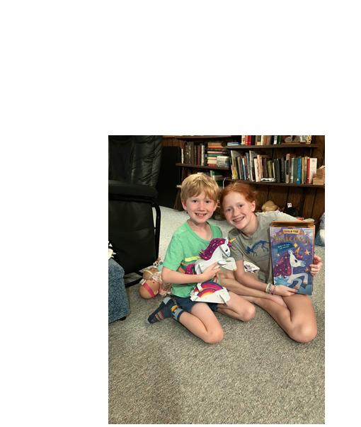 Two children sitting on the floor holding books

Description automatically generated